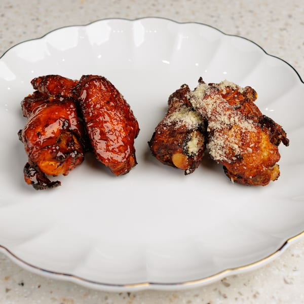 Two types of Fried CTs chicken wings on a white scalloped plate: glazed and parmesan-dusted.