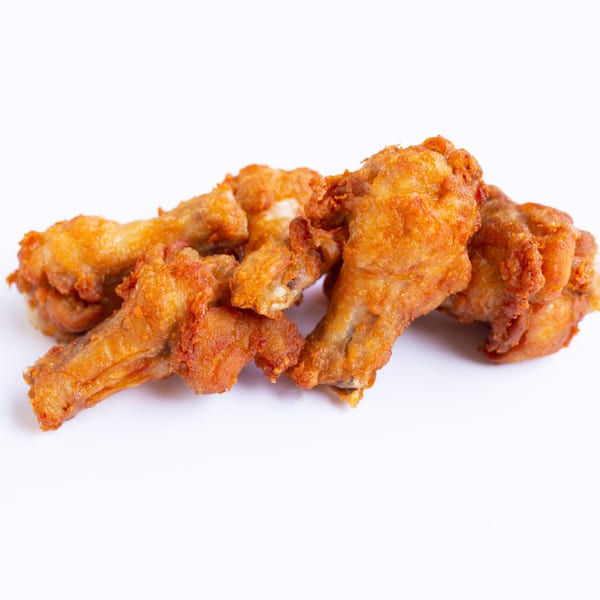 A close-up of several golden-brown fried chicken drumettes and wingettes on a white background.
